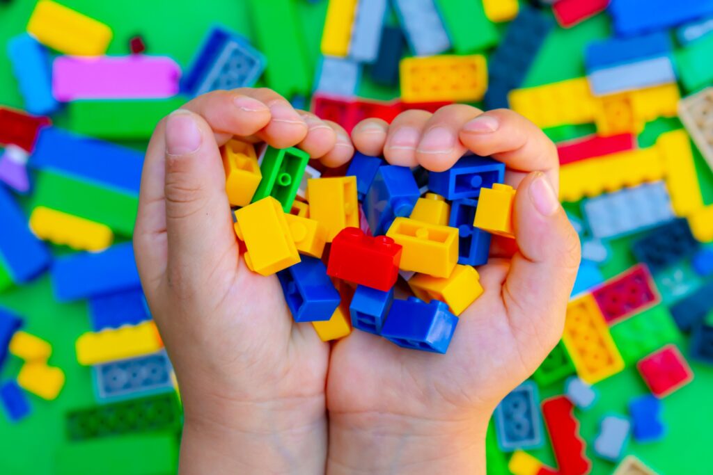 Mains d'un garçon ramassant des briques de Lego.