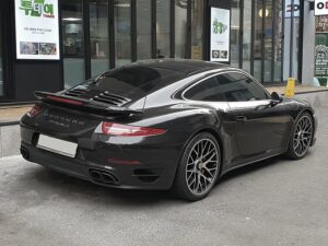 Porsche 911 turbo s noir garé devant une enseigne