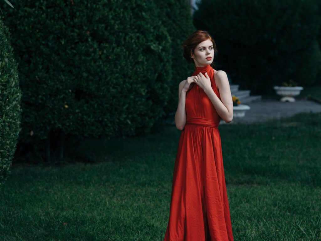 Photo d'une femme en robe rouge sans manche, posant pour une photo dans le jardin