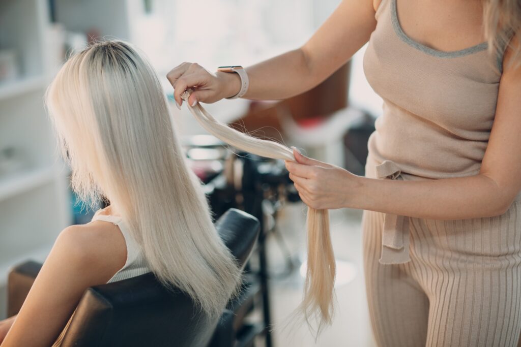 Femme au salon de coiffure faisant une coupe de cheveux mi-long blanche par la coiffeuse