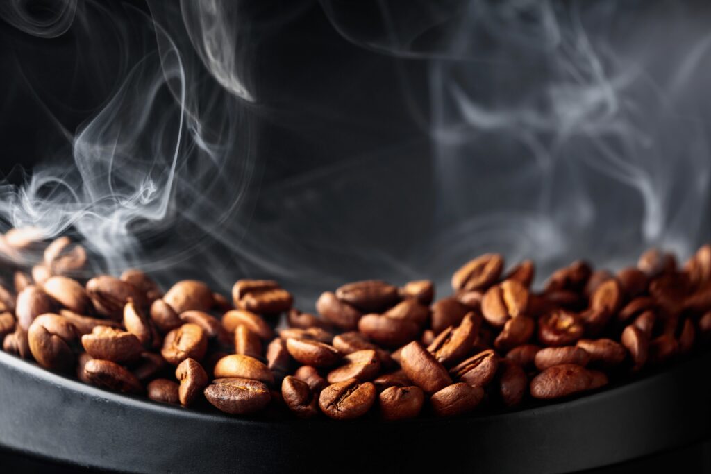 Des grains de café grillés dégagent de la vapeur. Concept de torréfacteur café.