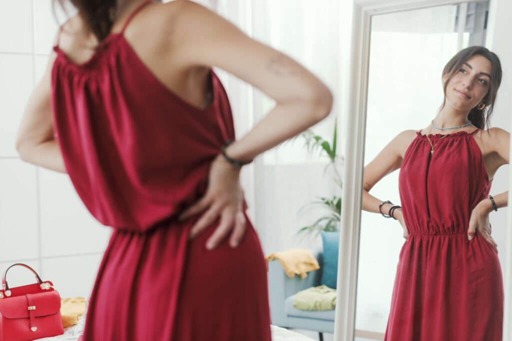 Femme posant devant un miroir, essayant une une robe rouge