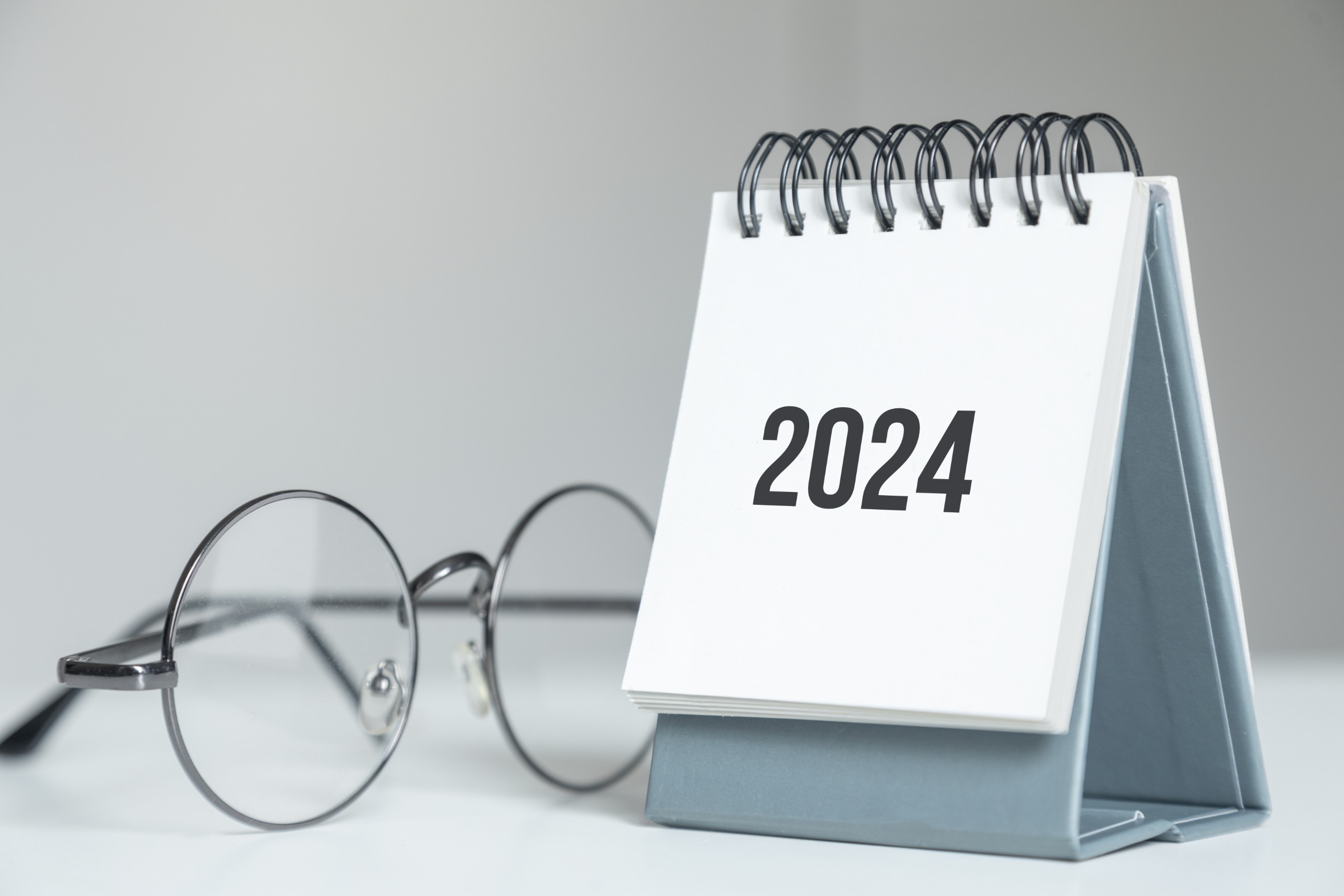 Calendrier de l'année 2024 imprimé, posée sur une table à coté d'une paire de lunette. Concept de planification chaque jour