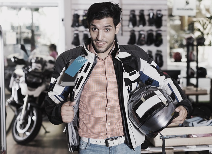 Un moteur dans une boutique Louis Moto, montre fièrement son nouveau blouson