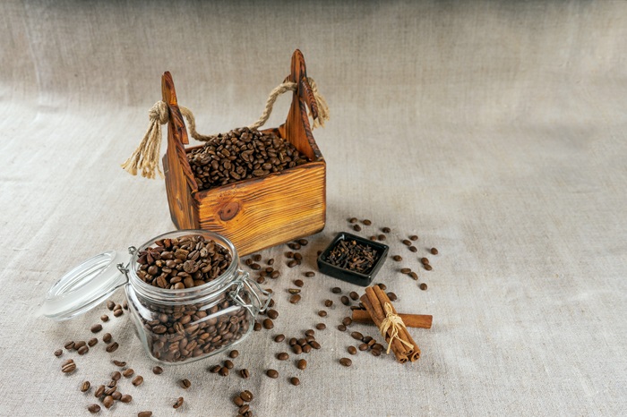 Un coffret et un bocal remplis de café avec des graines sur fond tissus gris. Concept de coffret café