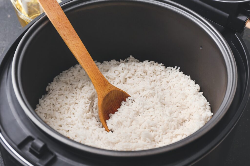 Un cuiseur riz multifonction ouvert avec du riz bouilli et une cuillères