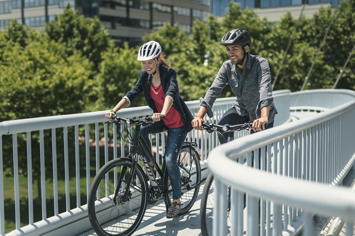 Un homme et une femme à vélo souriant discutent en pédalant dans la ville
