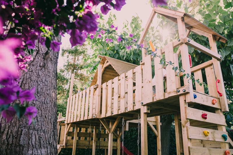 Une cabane enfant en bois dans le jardin, à coté d'un arbre