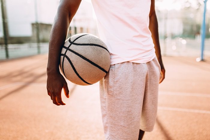 Un jeune garçon tient un ballon de basket dans la main le matin pour s'entrainer