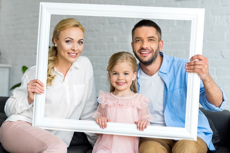 Un jeune couple avec leur enfant font une photo avec un cadre personnalisé famille