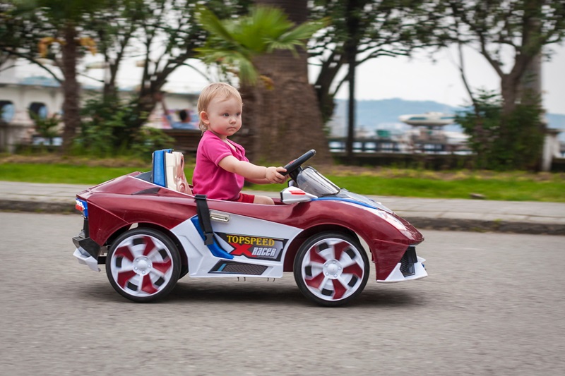 jeune fille conduit une voiture électrique pour enfant