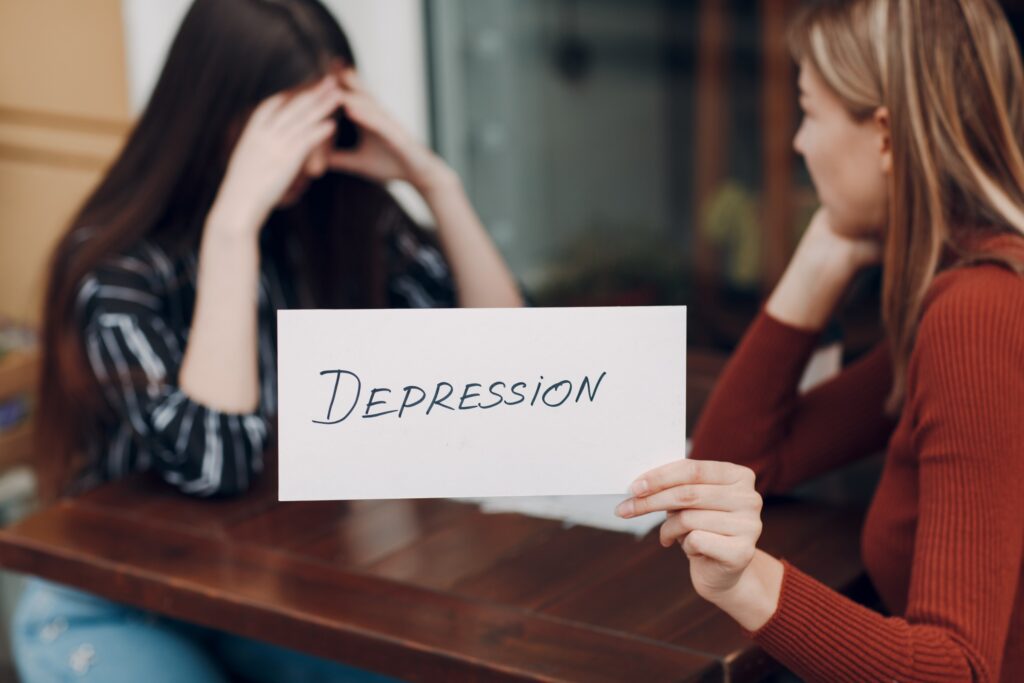 Femme en pleine dépression en face d'une amie avec une une pancarte dépression