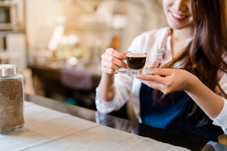 Une torréfactrice sert un café noir dans un verre transparent