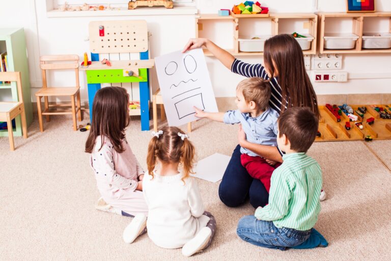 Une atsem entrain de travailler avec des enfants sur du dessin.