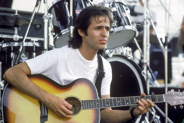 Jean-Jacques Goldman, jouant sa guitare, en attendant le début de son concert, photo de sa tournée en 1986