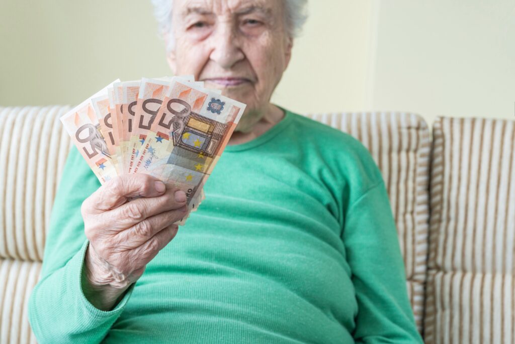 Une vieille femme tient des billets de banque dans la main. Concept de revalorisation retraite