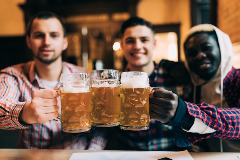 3 hommes trinque avec 3 verres pleines de bière sans alcool au comptoir d'un pub