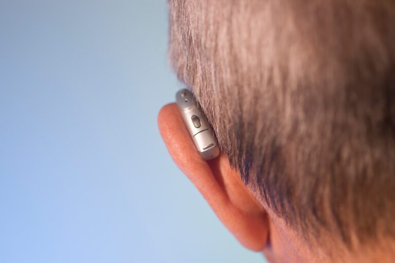 Gros plan sur l'appareil auditif dans les oreilles d'un vieil homme blanc caucasien portant avec des cheveux gris