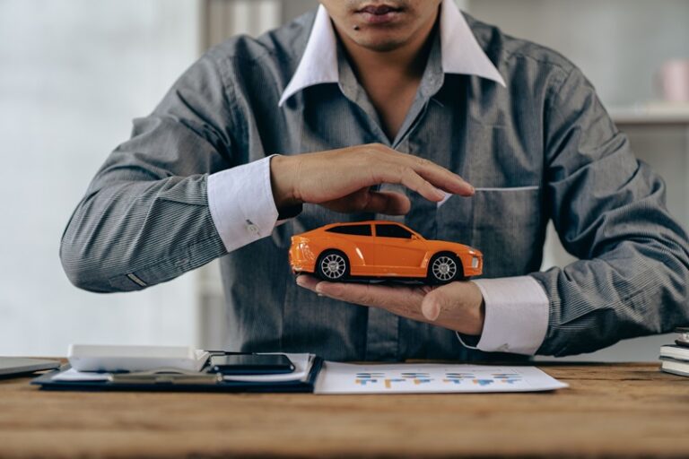 Petite voiture orange protégée par un homme. Concept d'assurance auto