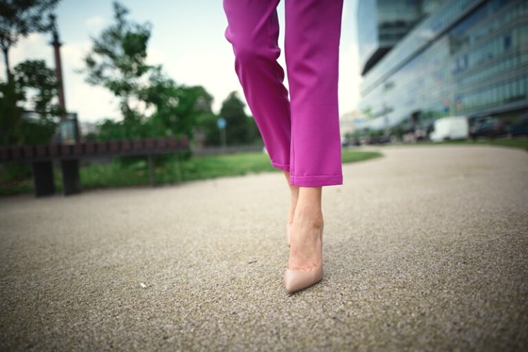 Une femme en pantalon fluide rose, en train de marcher dans la ville