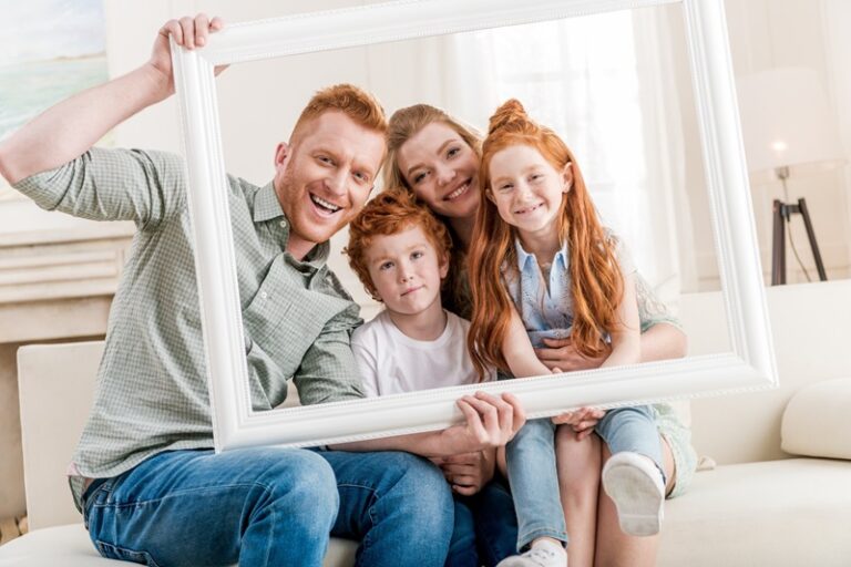 Une famille se réunit derrière un cadre photo pour une photo