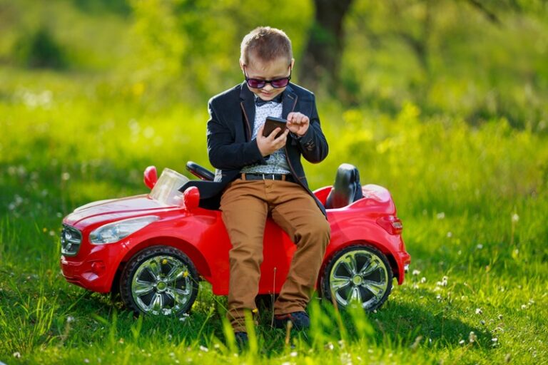 Un jeune garçon, à coté de sa Voiture électrique enfant